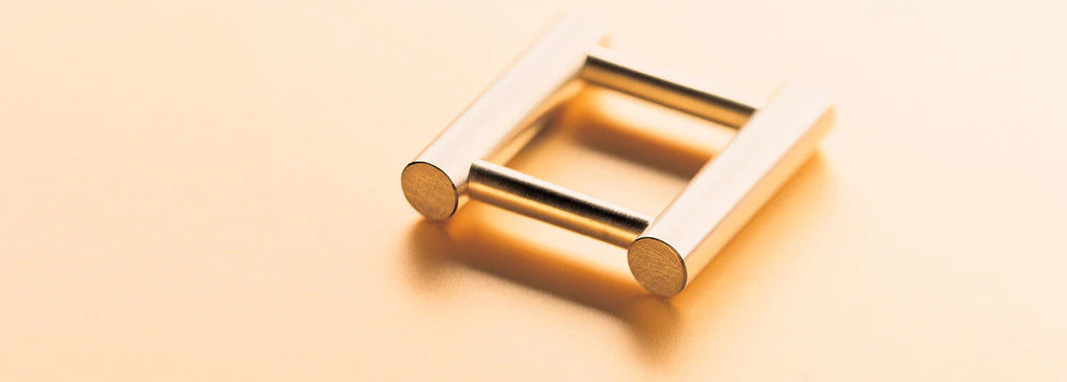 carl dau gold ring with steel rods, on a peach background